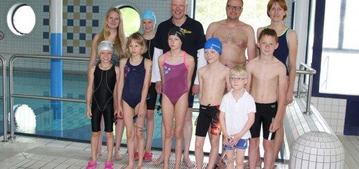 junge Schwimmerinnen und Schwimmer mit Trainer