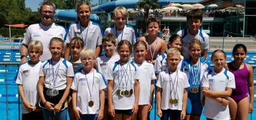 Gruppe junger Schwimmerinnen und Schwimmer mit Medaillen und Trainer