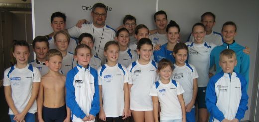 Gruppe junger Schwimmerinnen und Schwimmer mit Trainern