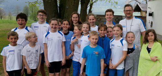 Gruppe junger Schwimmerinnen und Schwimmer mit Trainer